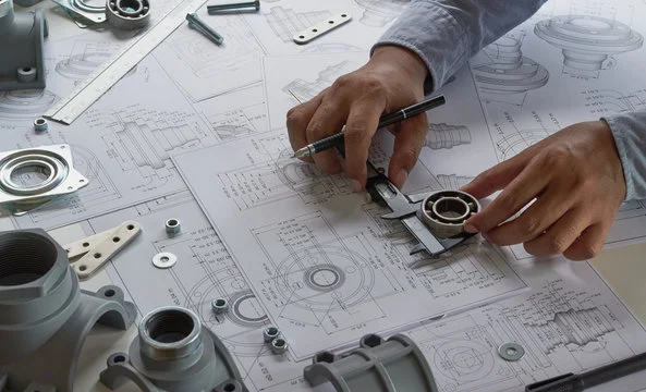 Engineer reviewing technical blueprints and mechanical parts